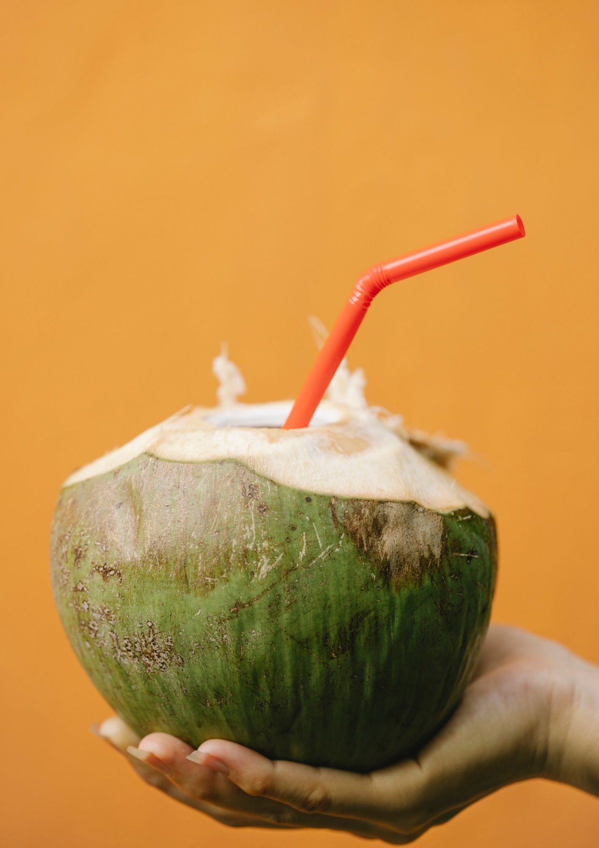 A fresh coconut with a red straw.