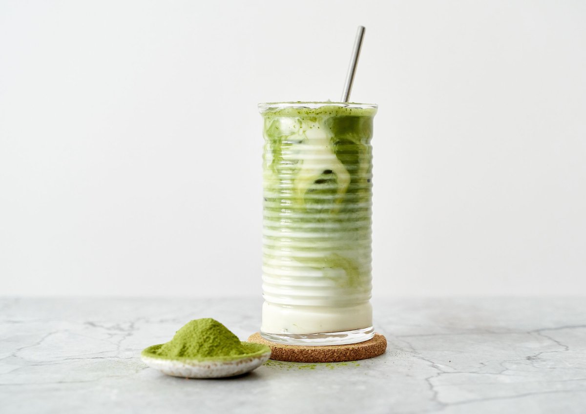 Iced matcha in a glass with a metal straw.