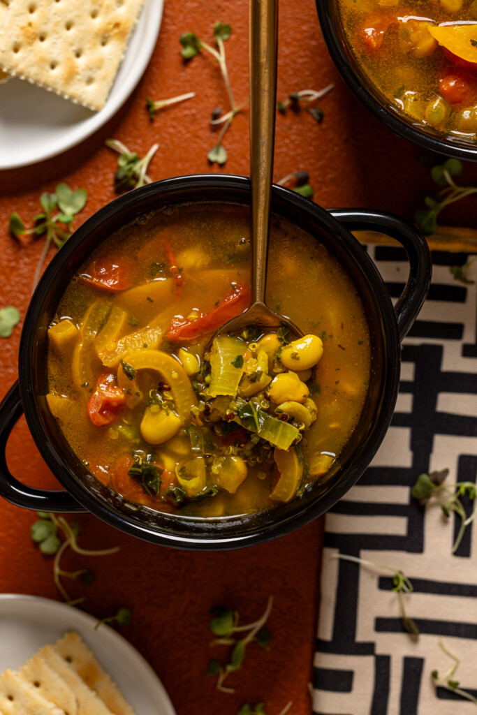 Up close shot of soup in a black bowl with a spoon.