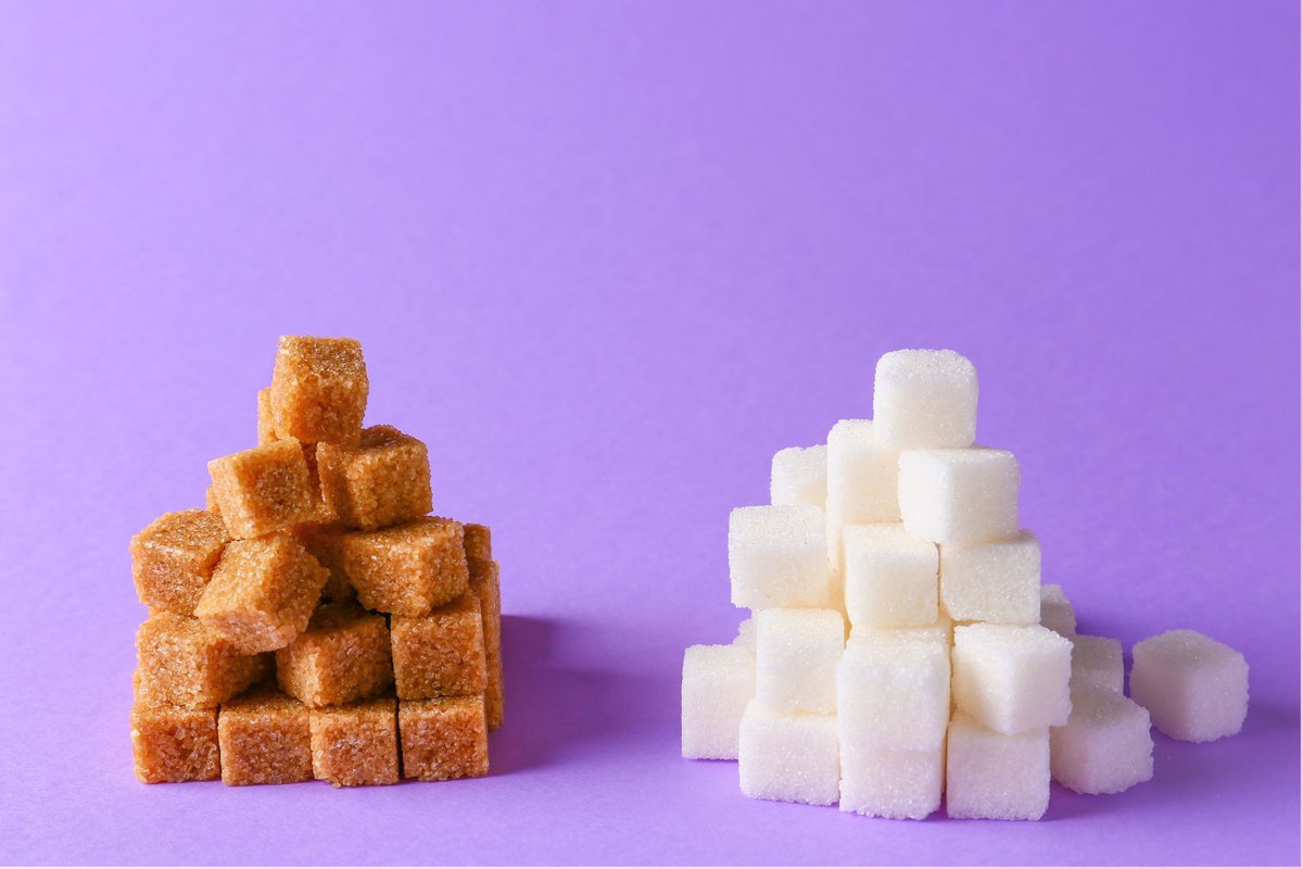 Brown sugar and white sugar cubes in two towers with a purple background.