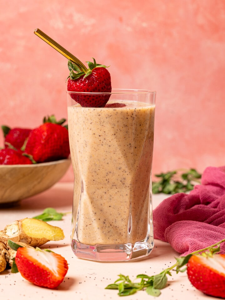 One glass of smoothie with fresh strawberries, ginger, and herbs.