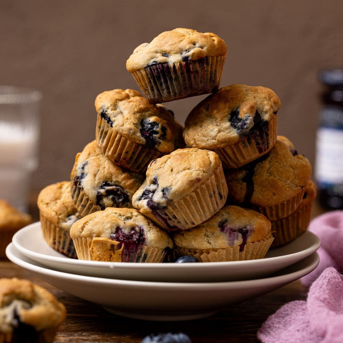 Stacked muffins on two plates with milk in the background.