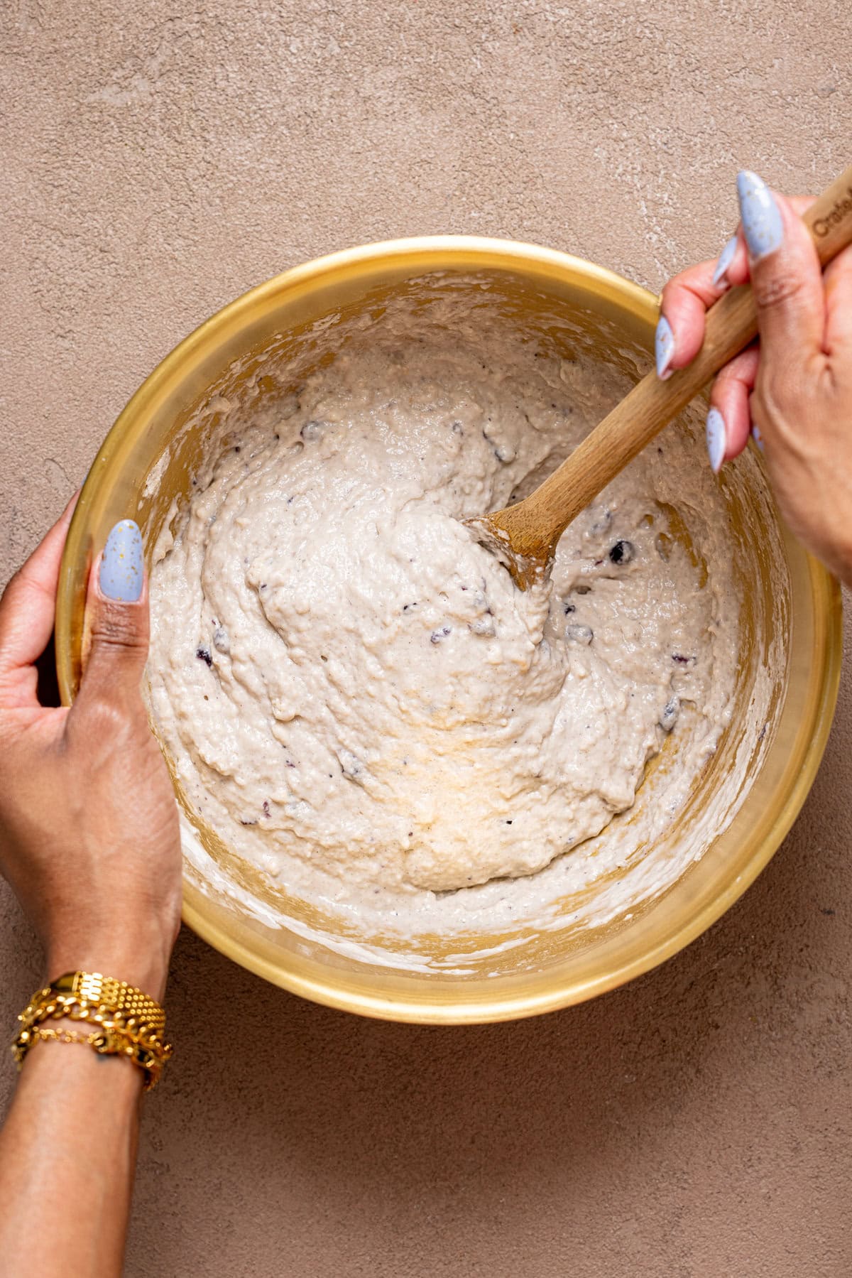 Muffins batter being stirred with a wooden spoon in a bowl.