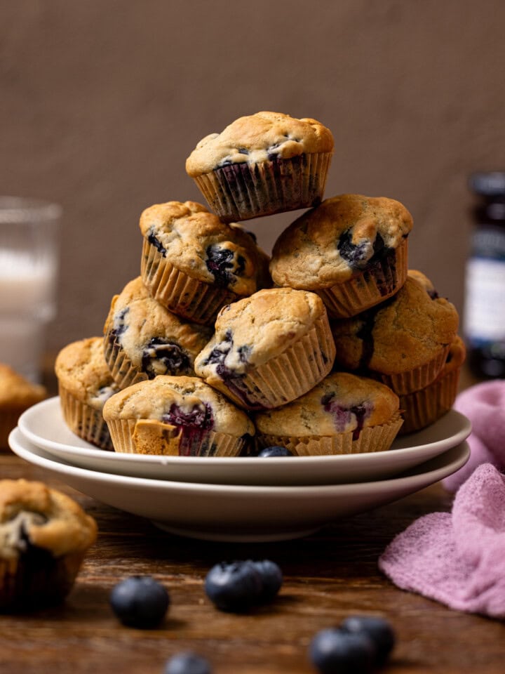 Stacked muffins on two plates with milk in the background.