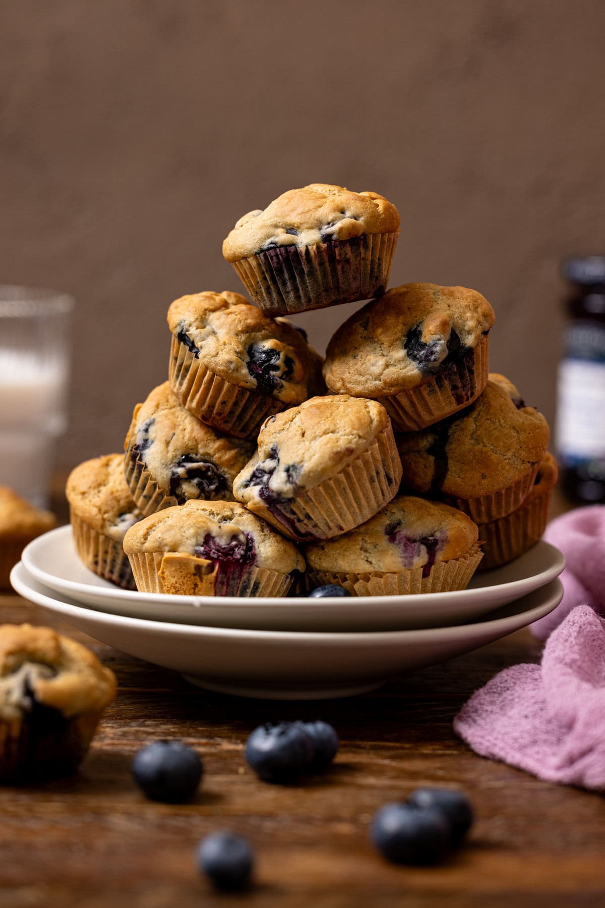 Stacked muffins on two plates with milk in the background.