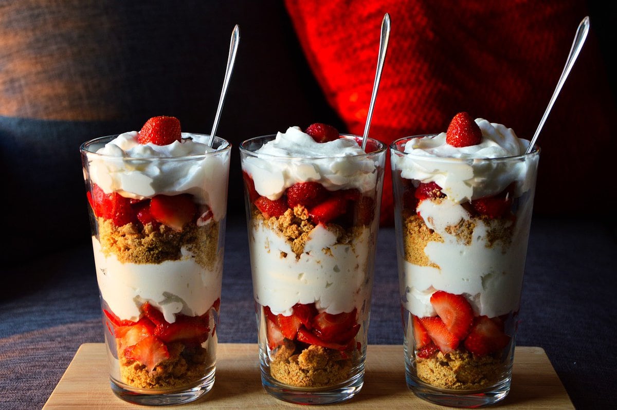 Glasses filled with yogurt parfait and spoons.