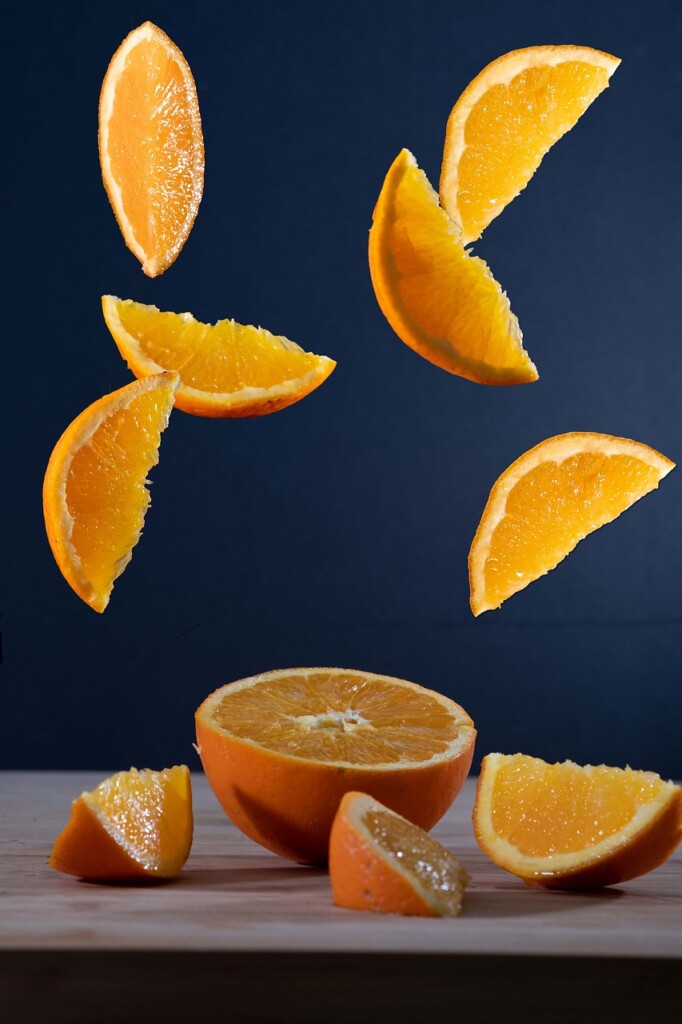 Sliced oranges in the air and on a table.