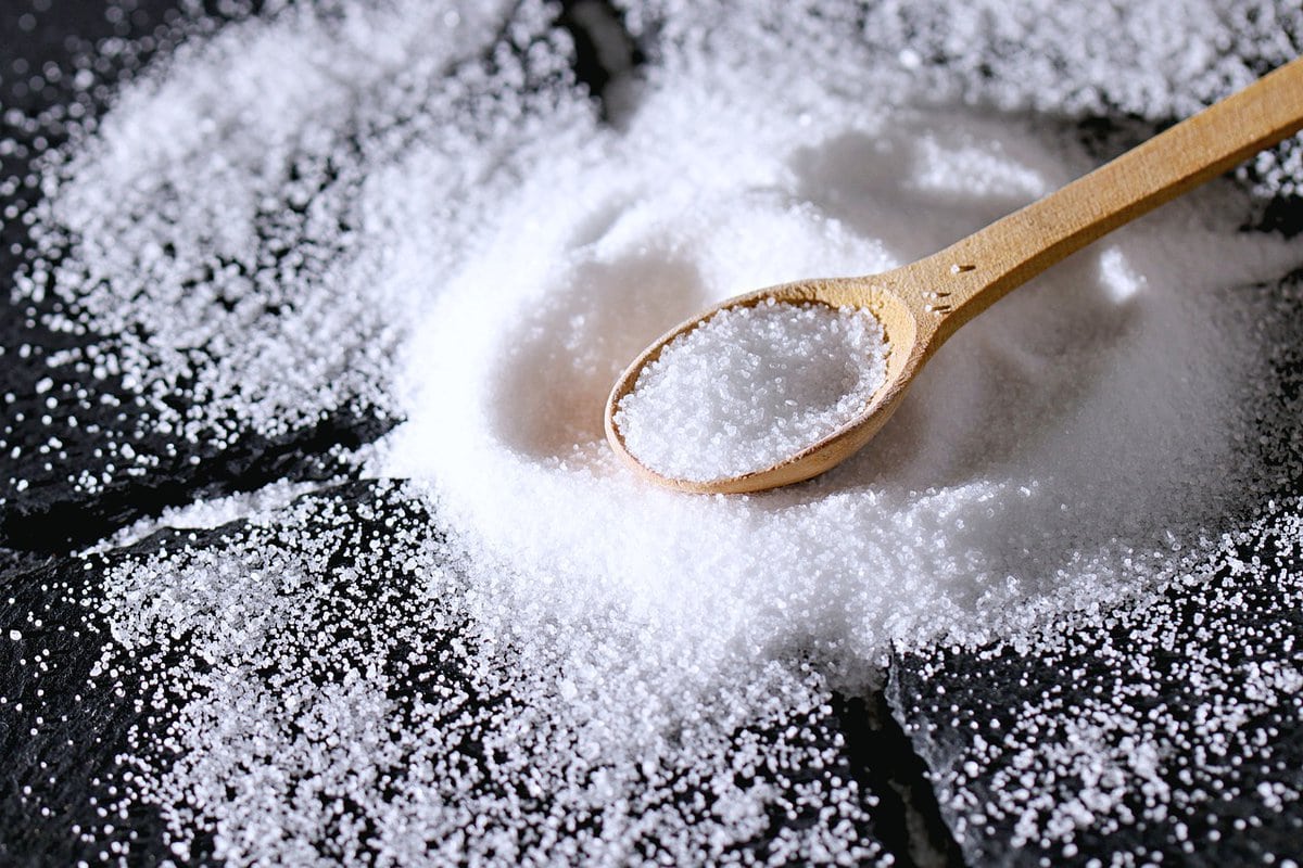 Image of salt on a surface with a wooden spoon.