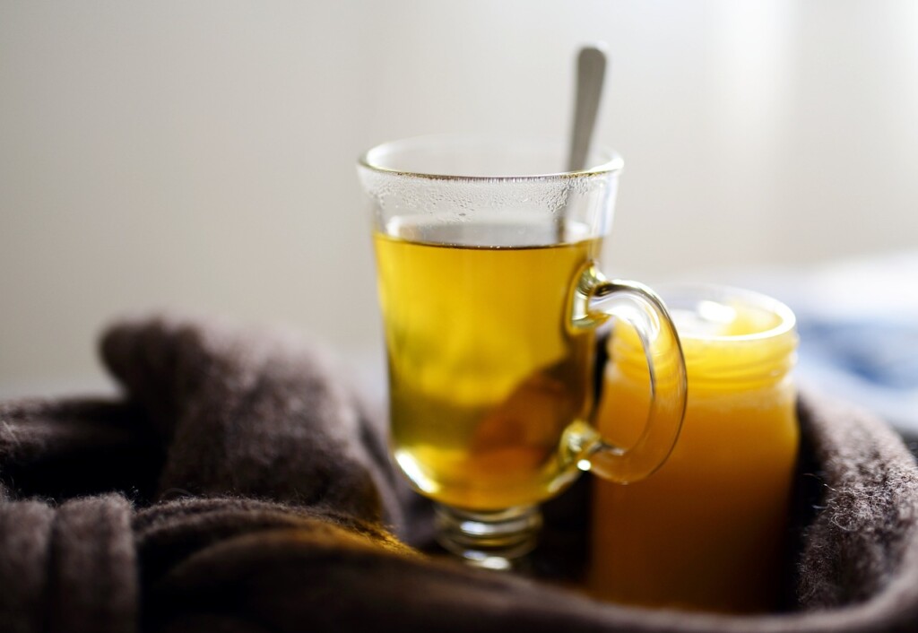 Glass mug with tea and honey on a blanket.