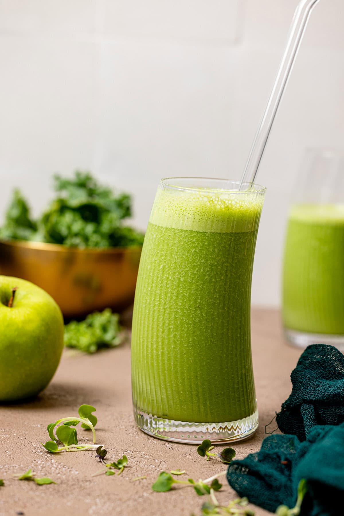 Green smoothie in a glass with fruit + veggies.