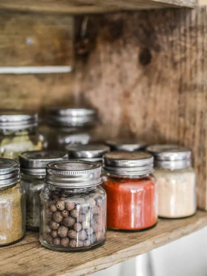 Jars of herbs and spices in a wooden cabinet.