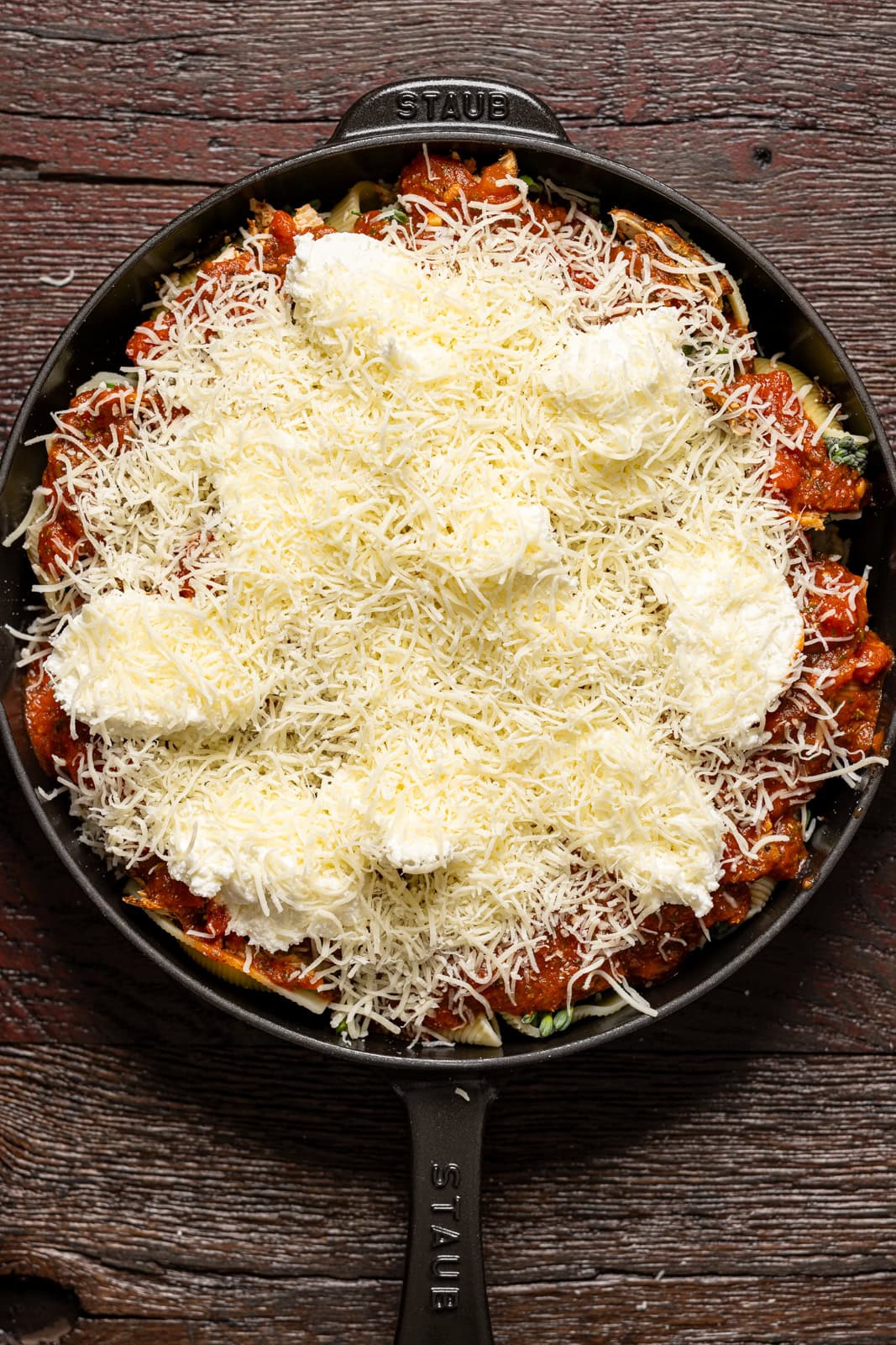 Layer of cheese atop ingredients in a skillet.