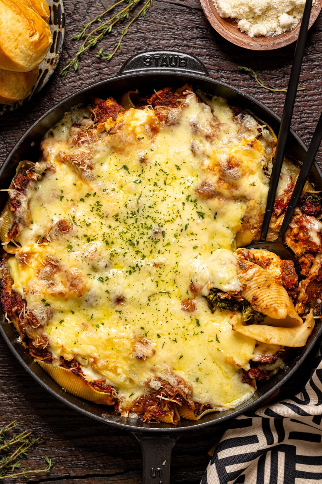 Baked stuffed shells in a skillet with two spoons.