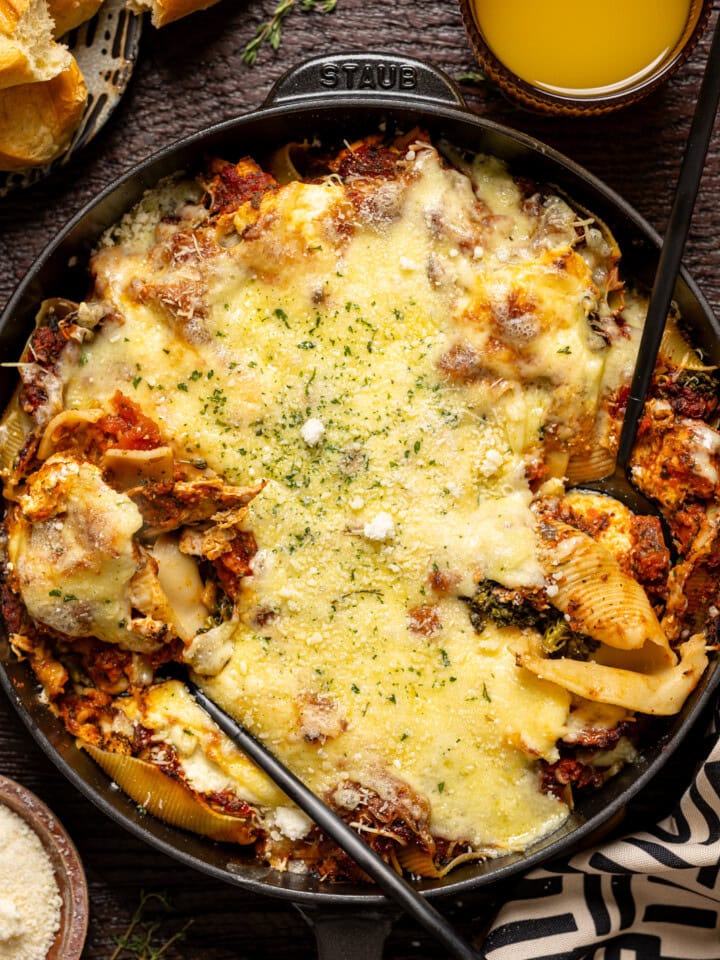 Stuffed shells scooped with two spoons in a skillet.