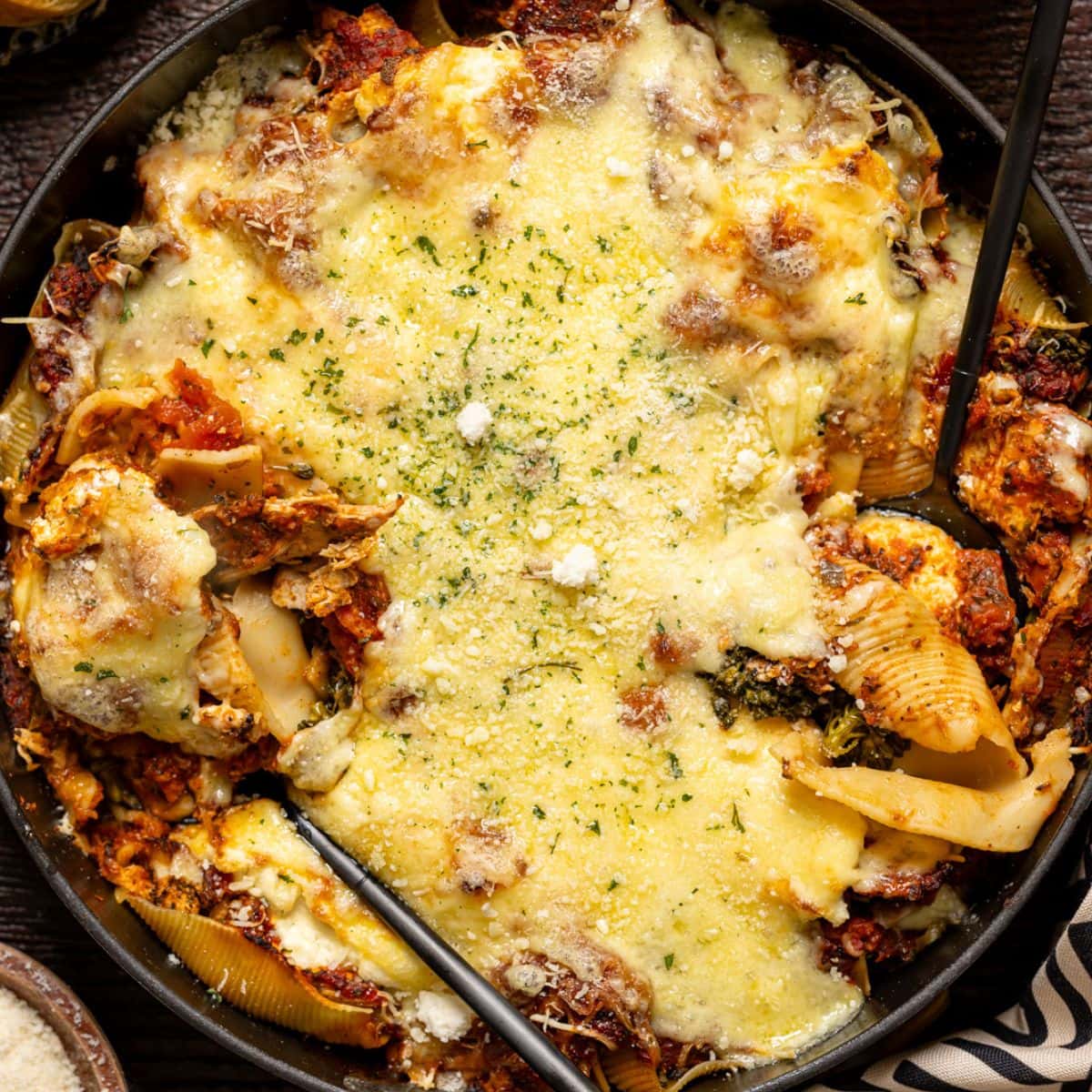 Stuffed shells scooped with two spoons in a skillet.