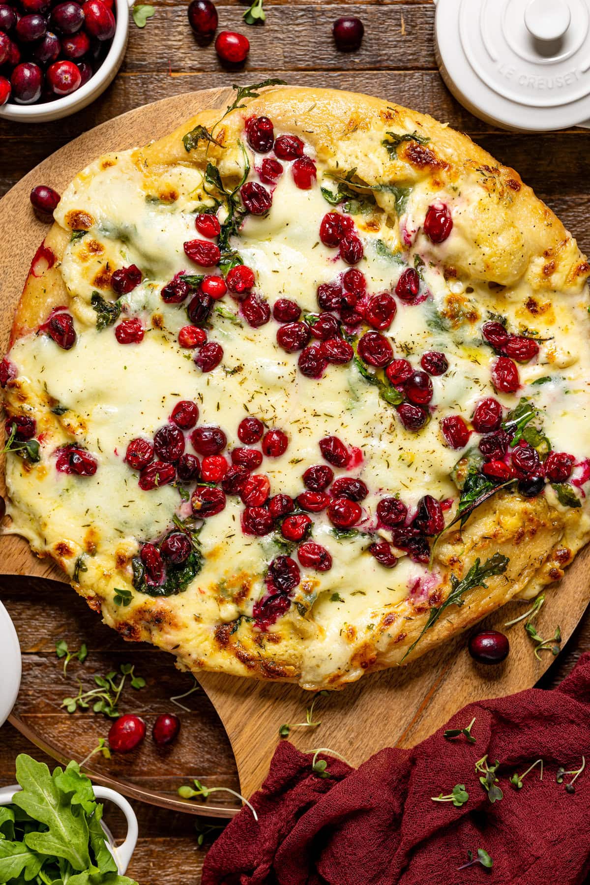 Baked pizza pie on a wooden board with cranberries.