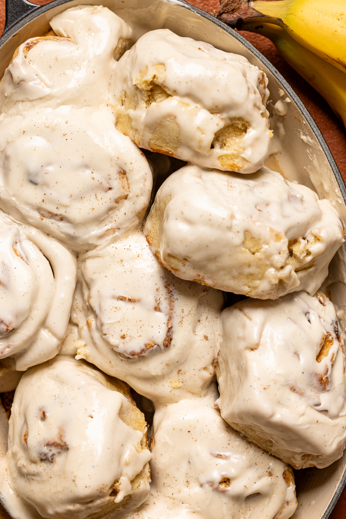 Banana Bread Cinnamon Rolls in a baking dish with a banana. 