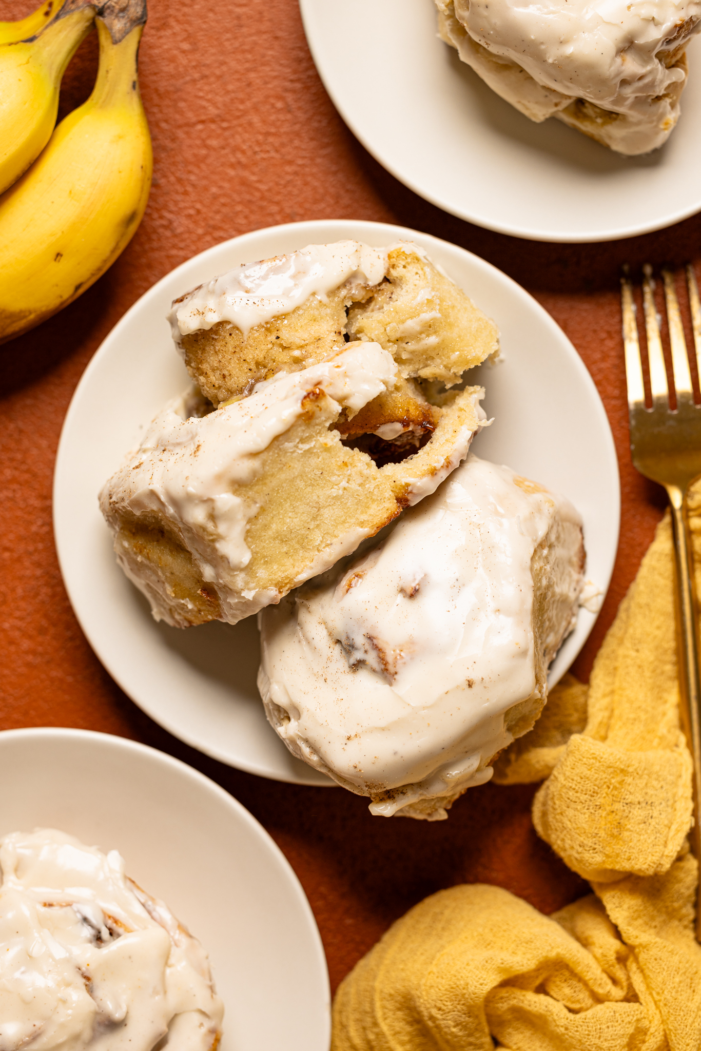 Cinnamon rolls on plates with a form and bananas. 