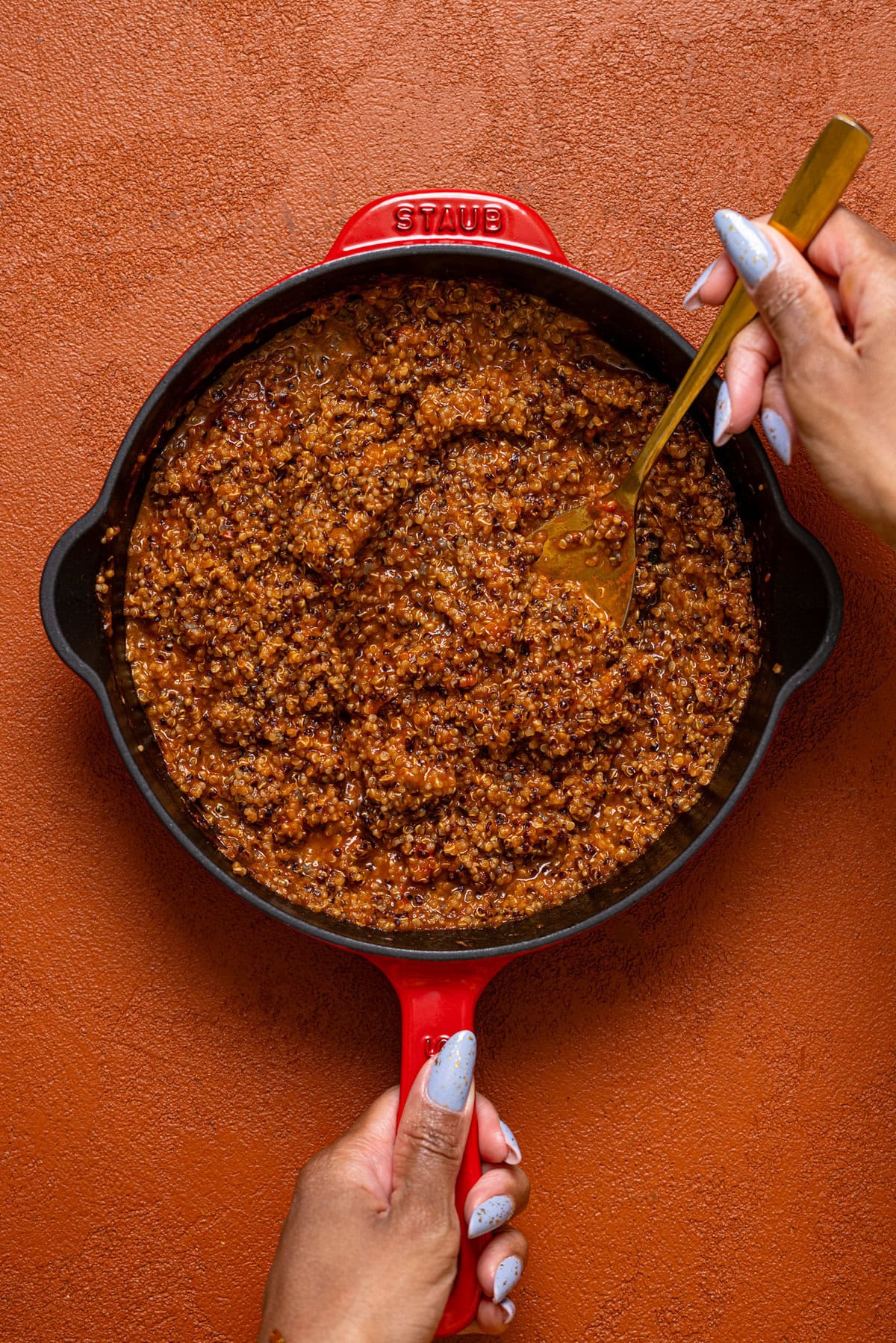 A skillet with sofritas quinoa being held with a spoon.