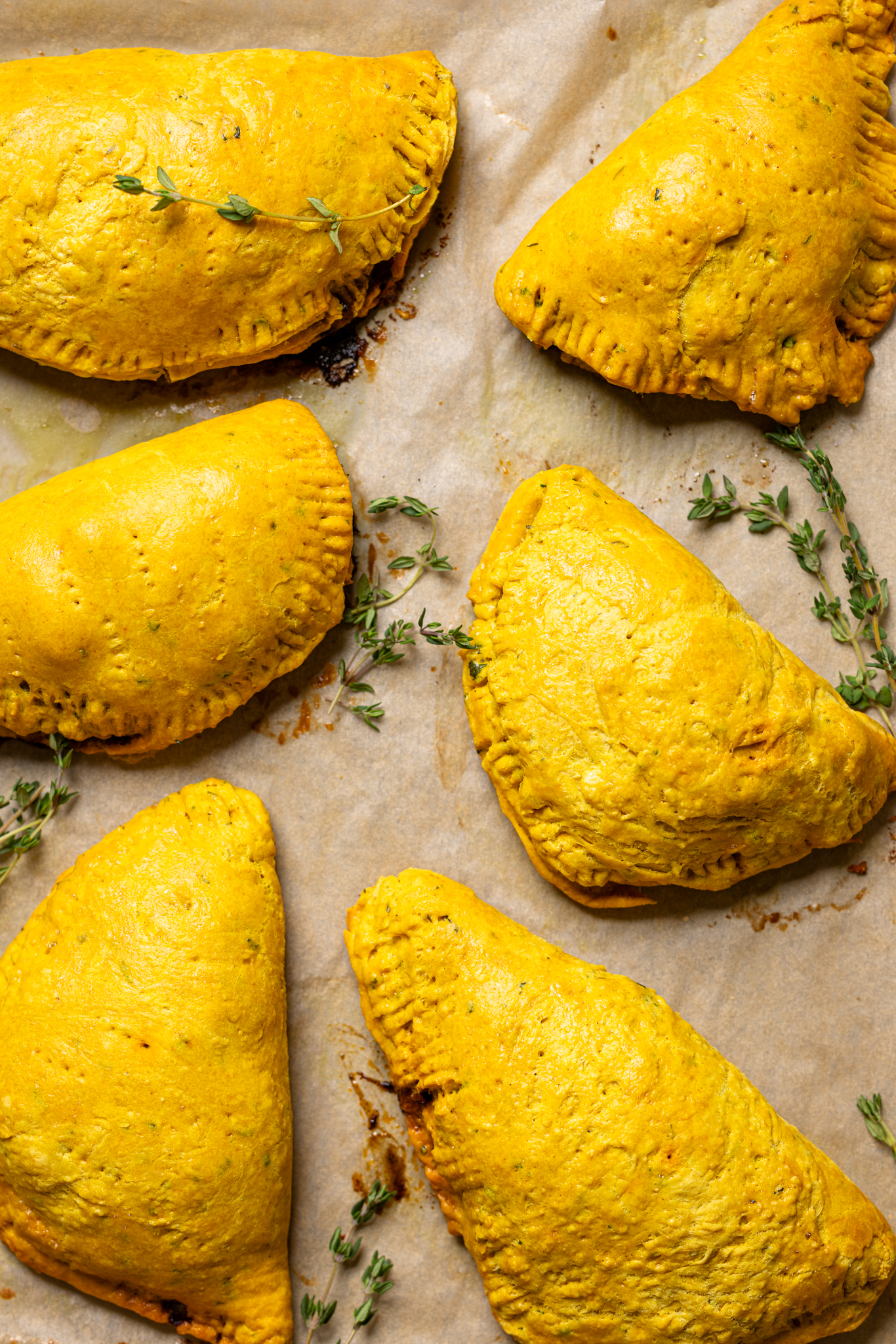 Jamaican beef patties baked on a baking sheet with parchment paper.