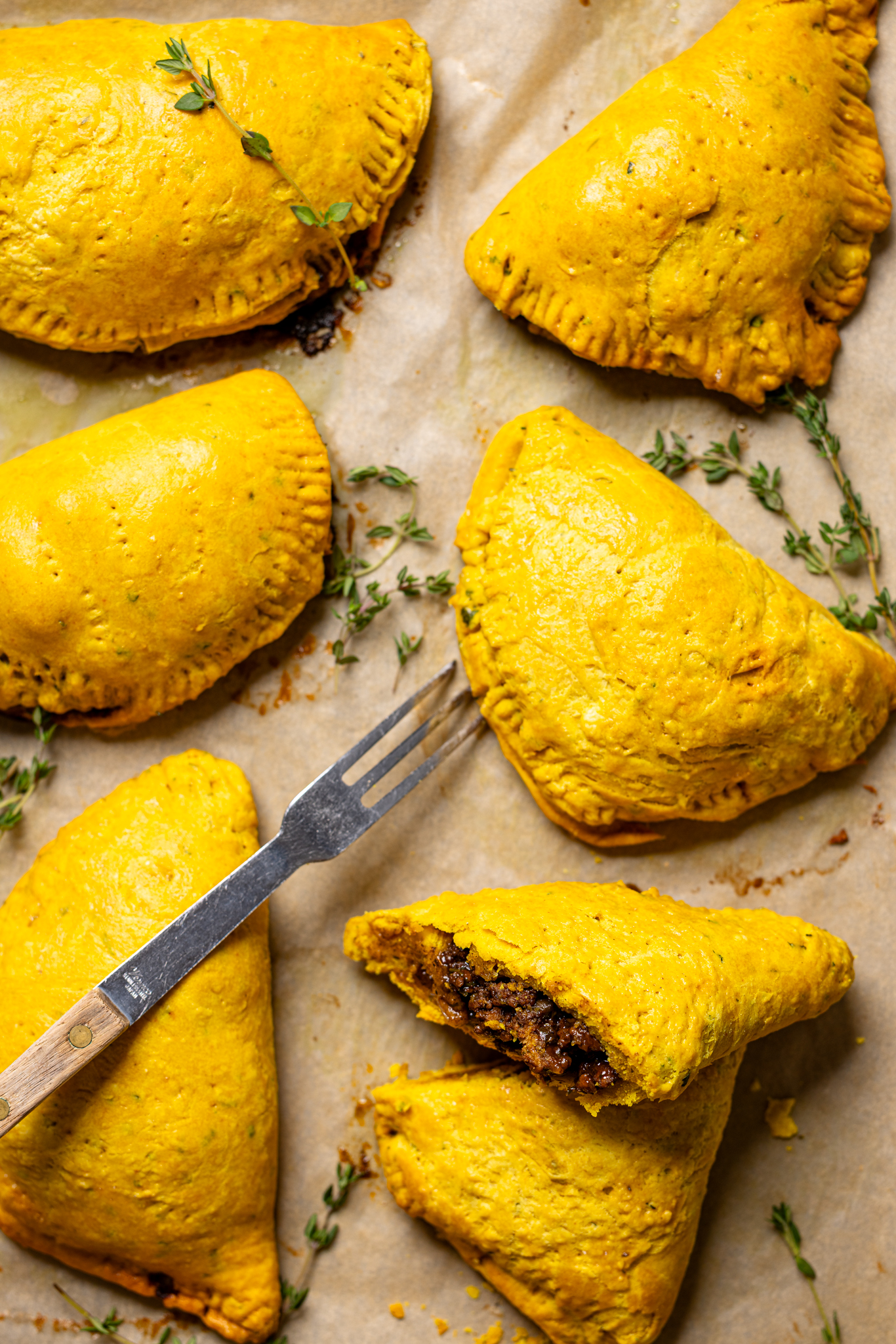 Image of Jamaican beef patties sliced open on a baking sheet with a fork.