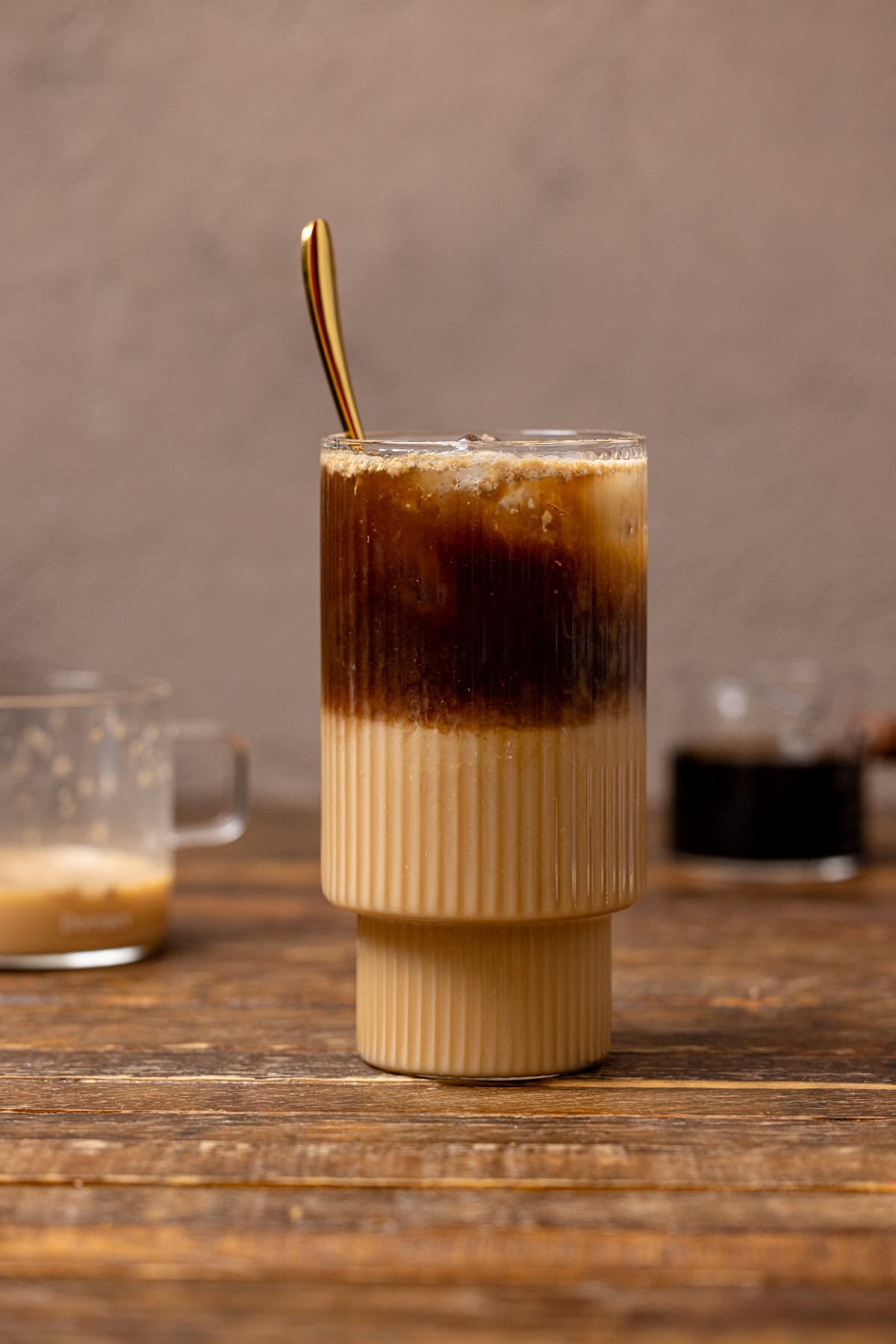 Dirty chai latte in a glass with a spoon.