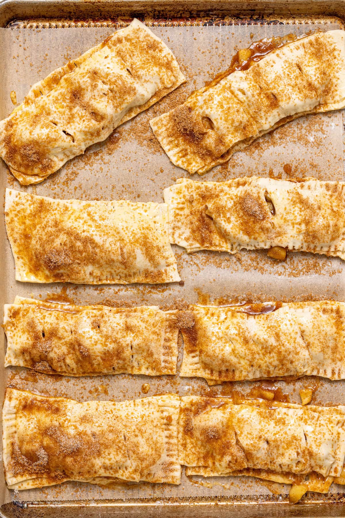 Assembled apple pies on a baking sheet with parchment paper.