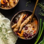 Vegan stew peas in a coconut bowl with herbs and a spoon.