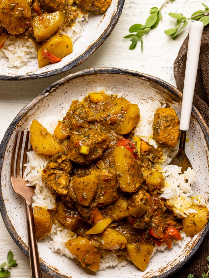 Up close shot of curry chicken dish with two forks on a white table.