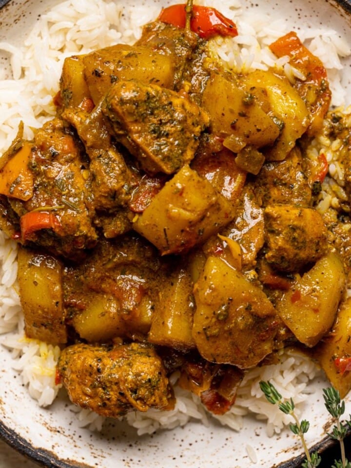 Up close shot of curry chicken in a bowl with herbs.