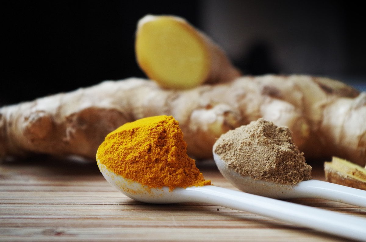 Ground ginger and turmeric in spoons on a table.