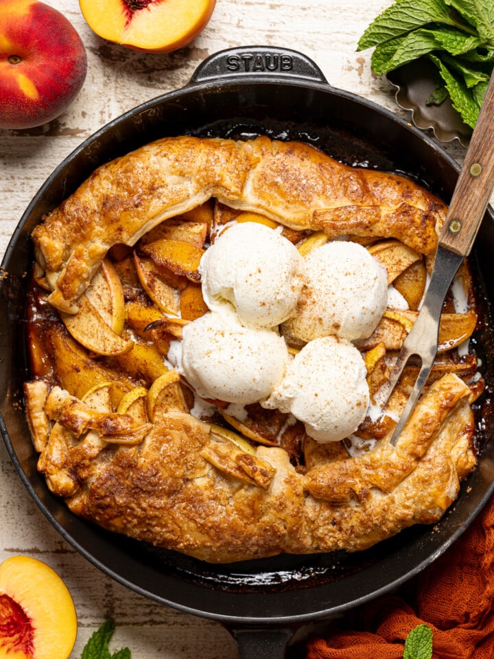 Galette in a black skillet with a fork and scoops of ice cream.