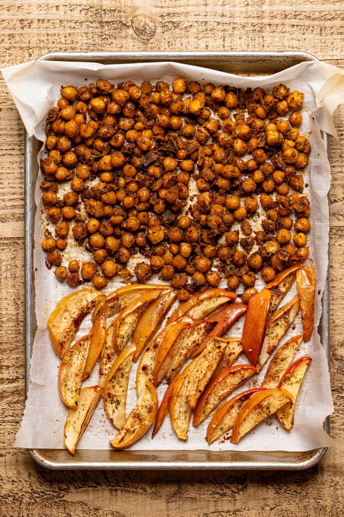 Chickpeas and apples roasted on a baking sheet with parchment paper. 