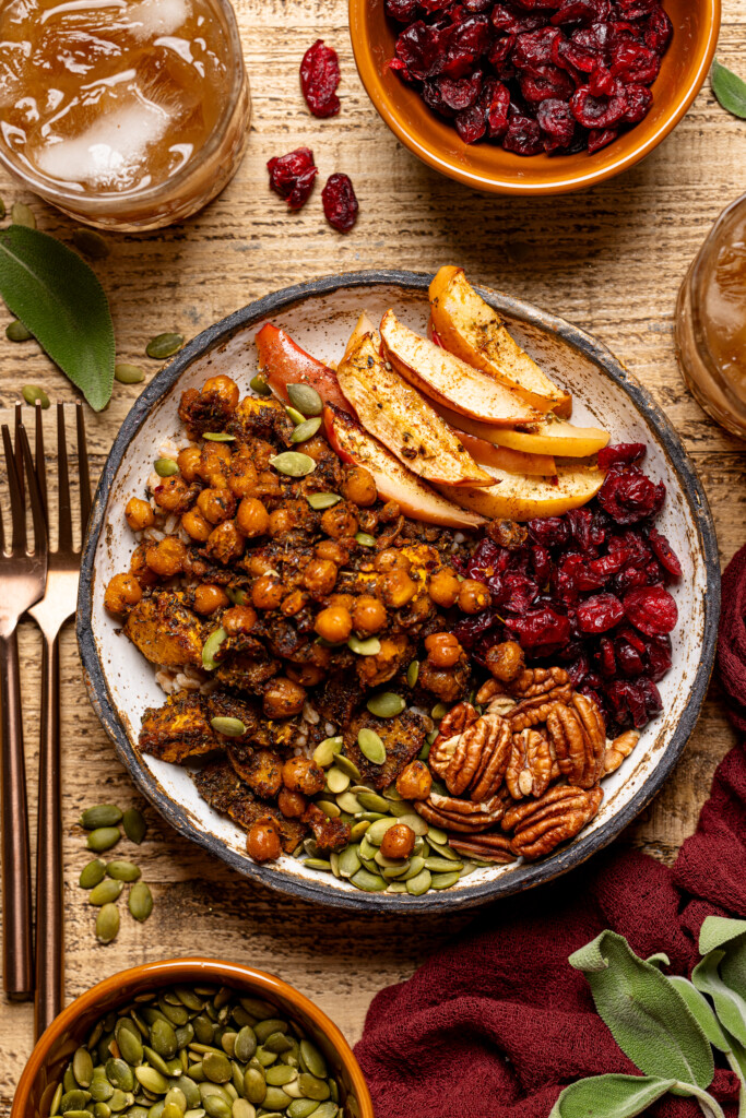 Up close shot of food bowl with two forks, glass of drink, and bowls of ingredients.