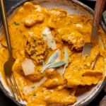 Up close shot of creamy ravioli in a low bowl with two forks.