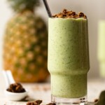 Glass of smoothie with a pineapple in the background and spices.