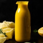 Dressing in a jar with a yellow napkin and lemon.