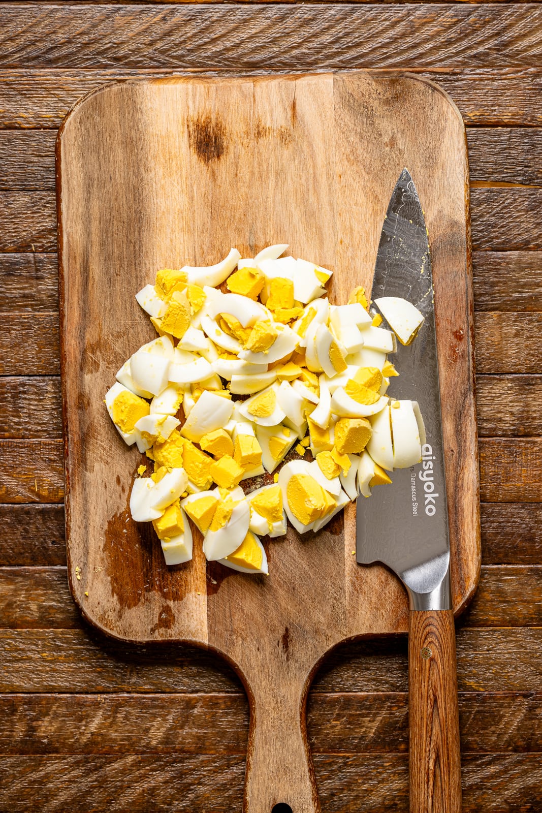 Chopped eggs on a cutting board with a knife.