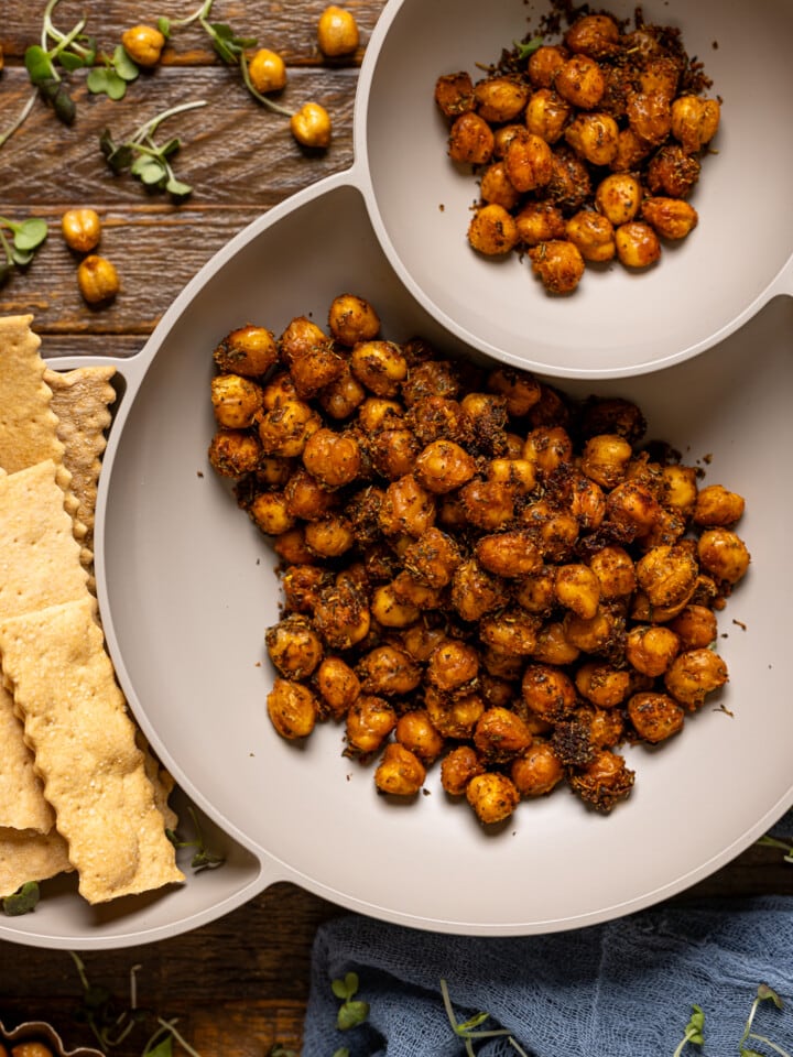 Close shot of chickpeas in a serving bowl with a side of crackers.