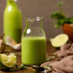 Two jars of dressing with lime, garlic, and cilantro in the background.