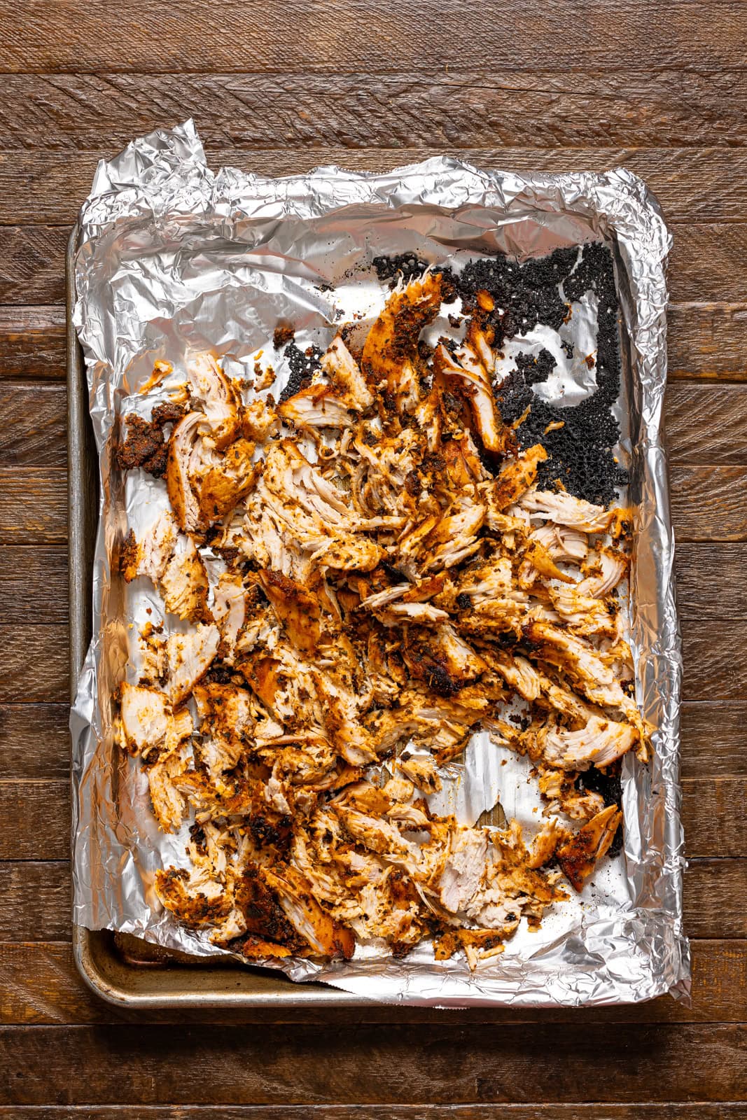 Shredded chicken on a baking sheet with foil.