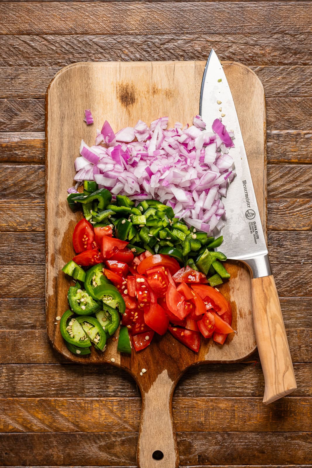 Veggies chopped on a cutting board with a knife.