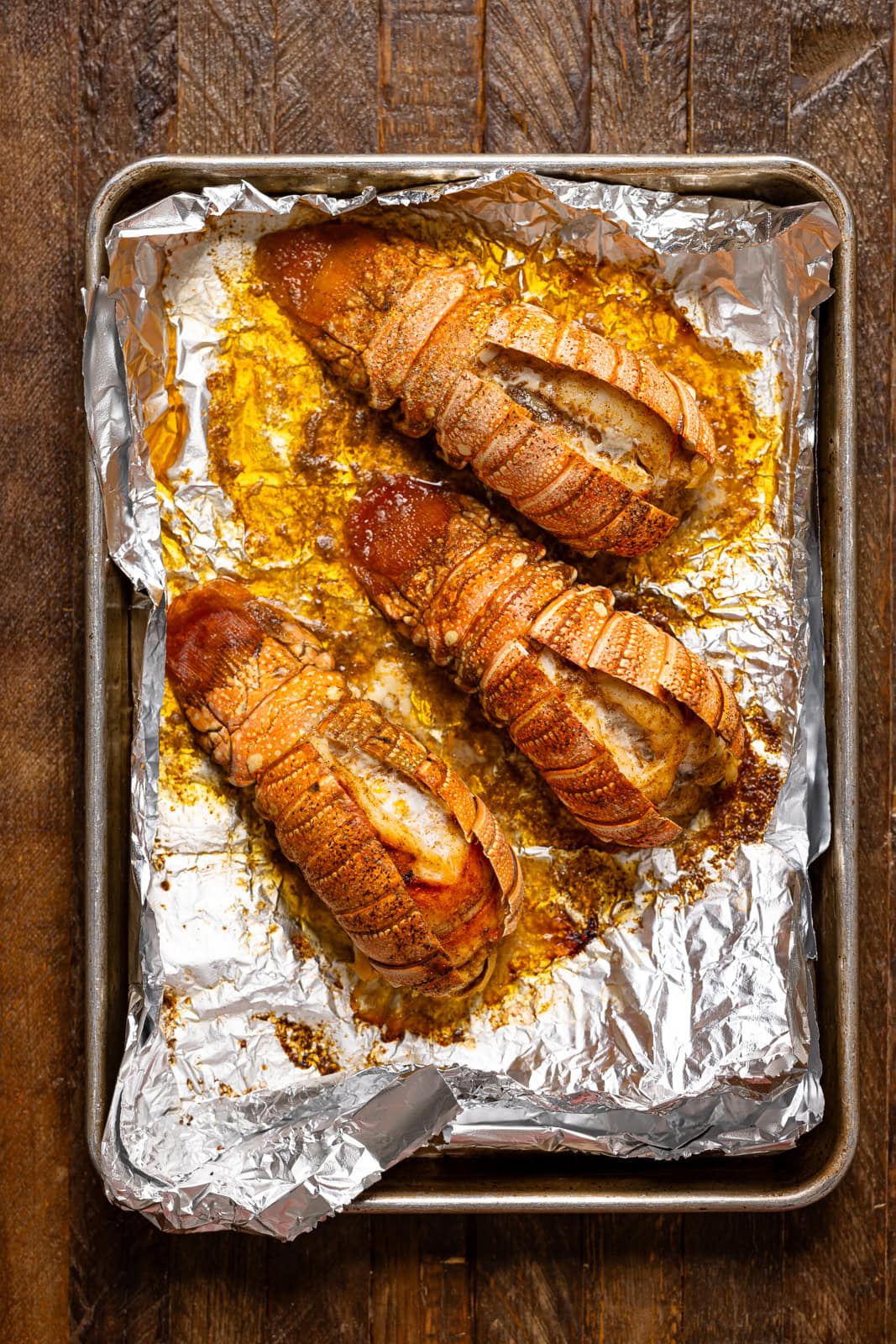 Cooked lobster tails on a baking sheet with foil paper.