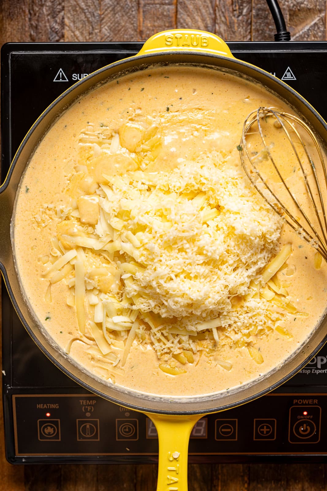 Mac and cheese sauce on a stovetop in a yellow skillet.