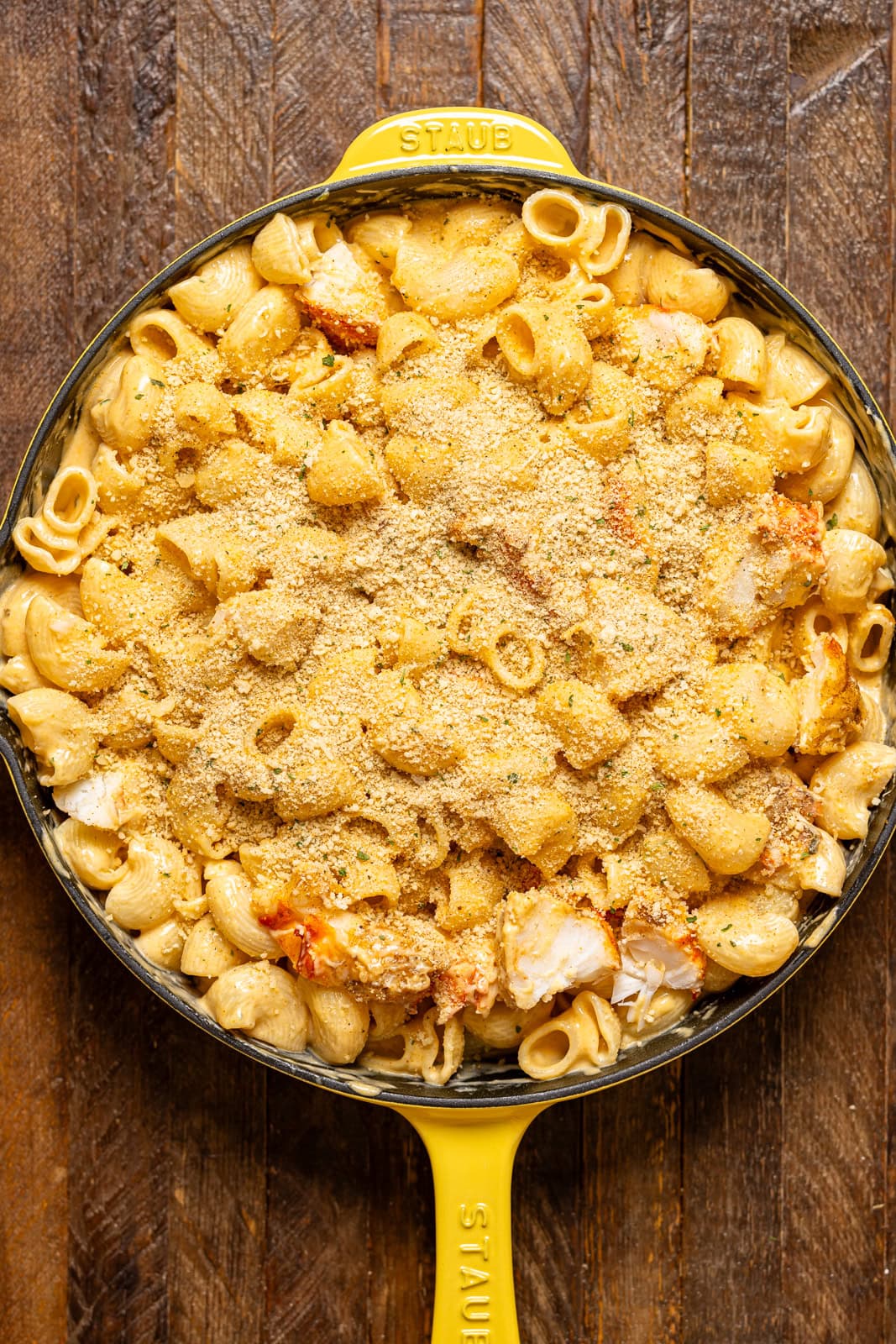 Breadcrumbs atop lobster mac and cheese in a yellow skillet.
