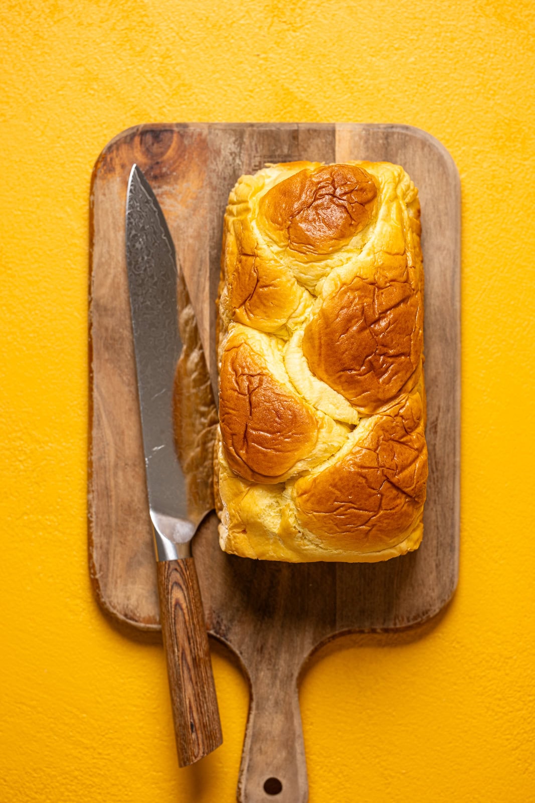 Loaf of brioche bread on a cutting board with a knife.