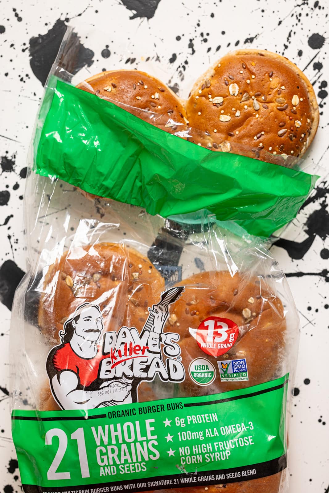 Burger buns in a bag on a white + black spot table.