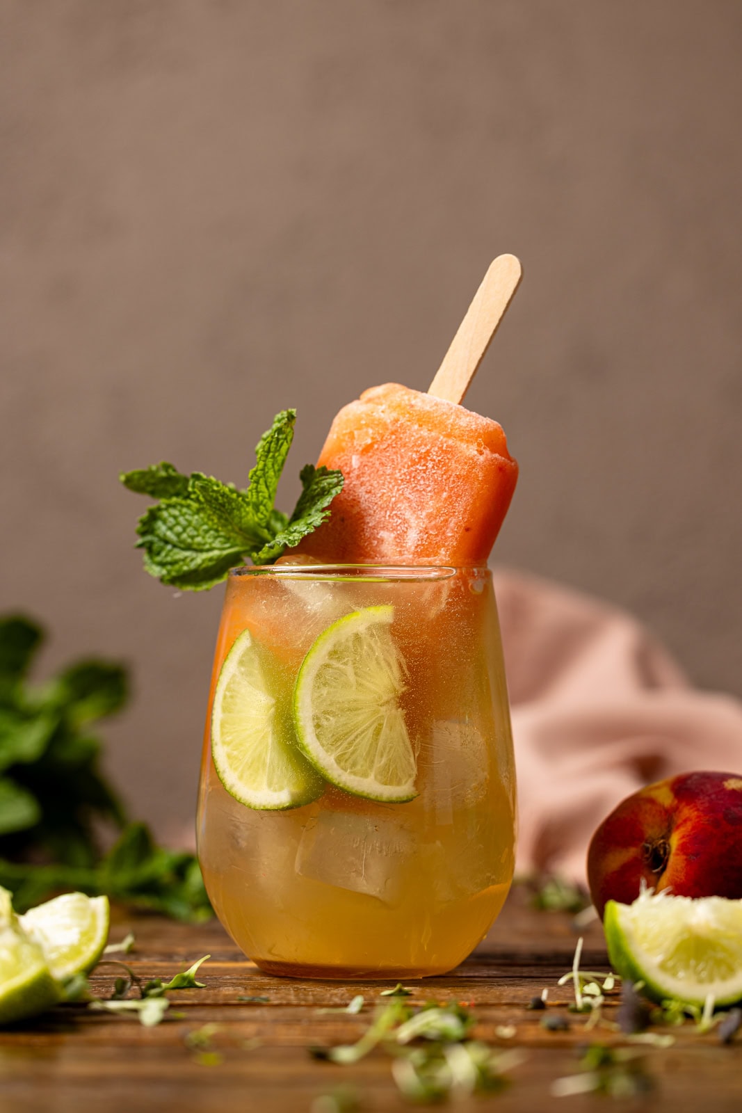 Mocktail drink with popsicle, lime, and a peach.