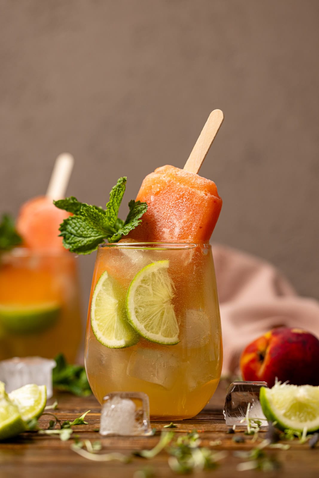 Peach Hot Honey mocktails with lime, ice cubes, and popsicles.