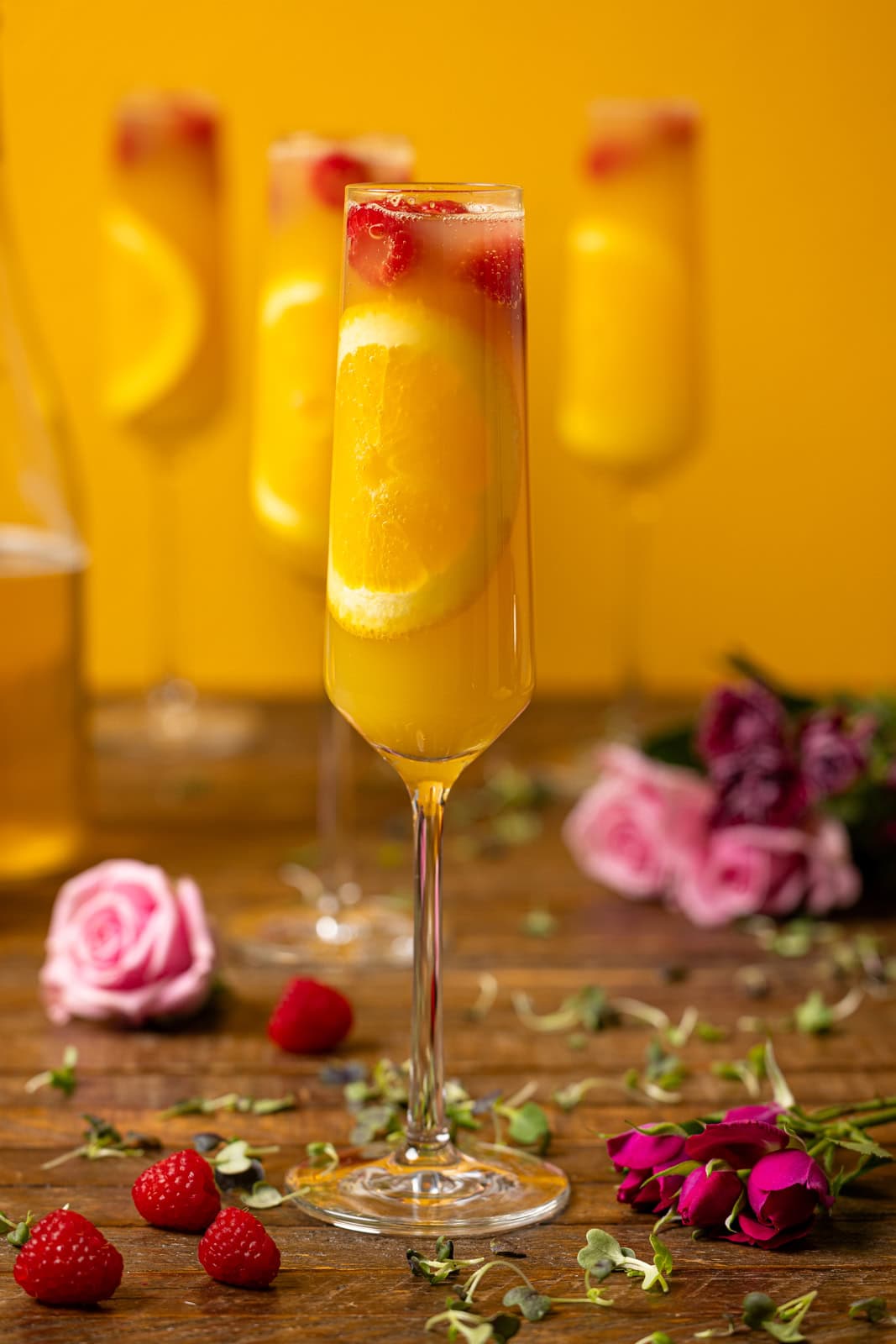 Glasses of mimosas with flowers and raspberries. 